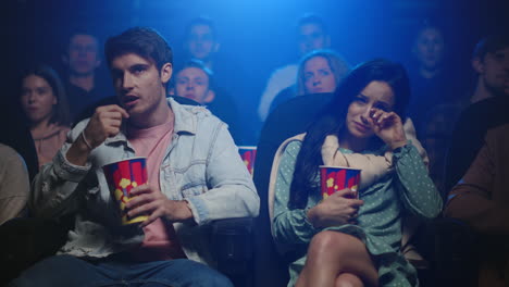 sad couple eating popcorn in cinema