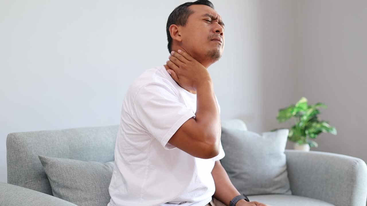 Uomo asiatico frustrato, dolore al collo con stress da burnout, affaticamento o eccesso di lavoro a casa