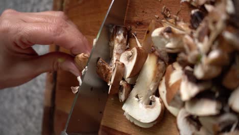tiro vertical de manos cortando champiñones portobello con cuchillo de cocina