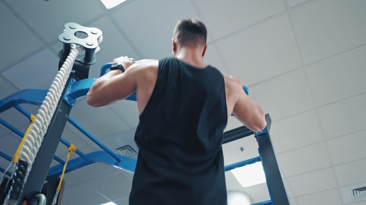 Back view portrait of a muscular man tightening in the gym. Guy bodybuilder tightening to improve his triceps and muscles indoors. Sports concept.