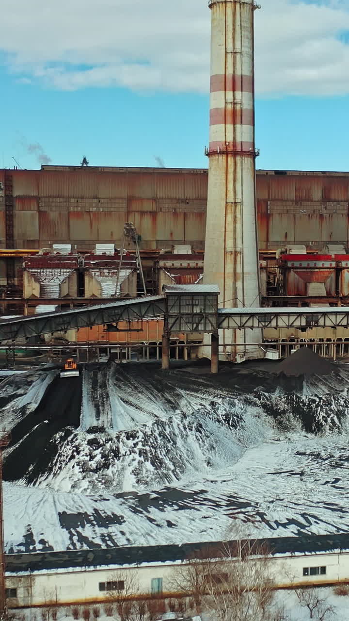 Heat power station with two high pipes is on the river bank on the outskirts of the city. Aerial view. Vertical video