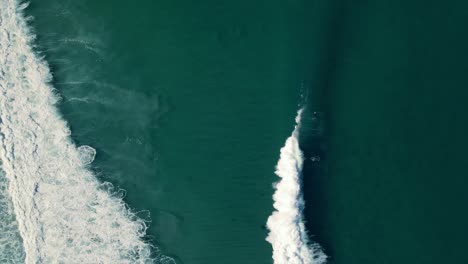 surfers duck dive waves drone view