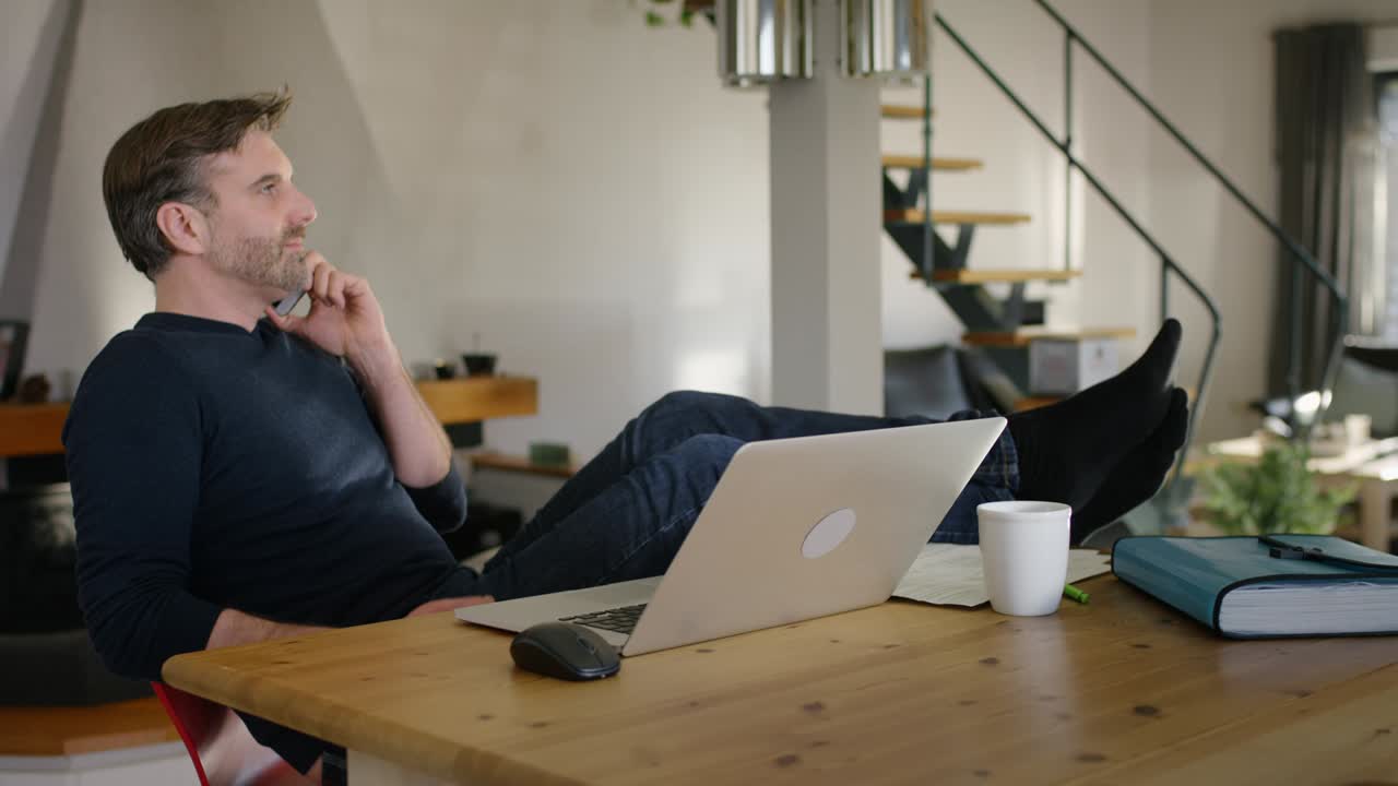 Handsome Man at home, with Feet on Table speaking on Mobile Phone
