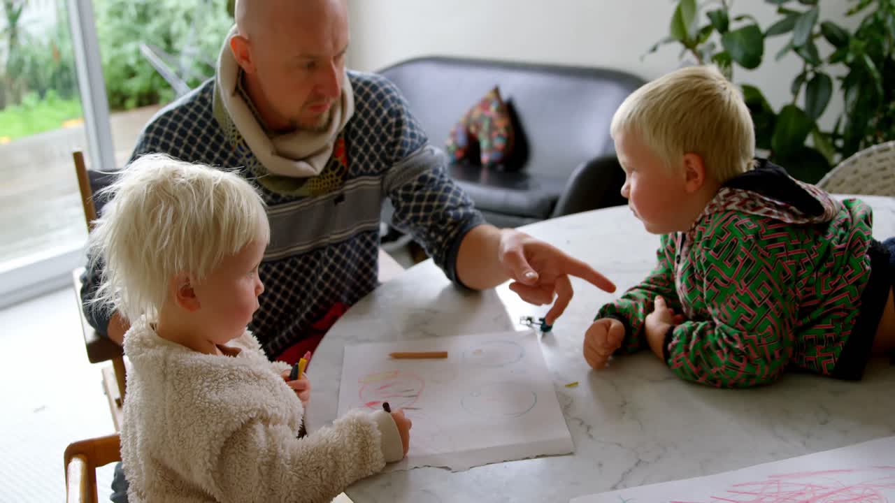 Vater hilft seinen Kindern beim Zeichnen zuhause 4k