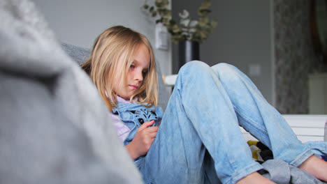 Foto-De-Retrato-De-Una-Joven-Rubia-En-El-Sofá-Mirando-El-Teléfono-Inteligente-En-La-Sala-De-Estar