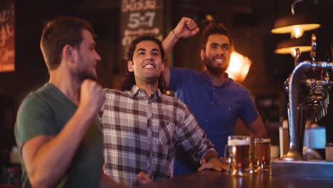 happy diverse male sport fans watching game at bar, celebrating and cheering