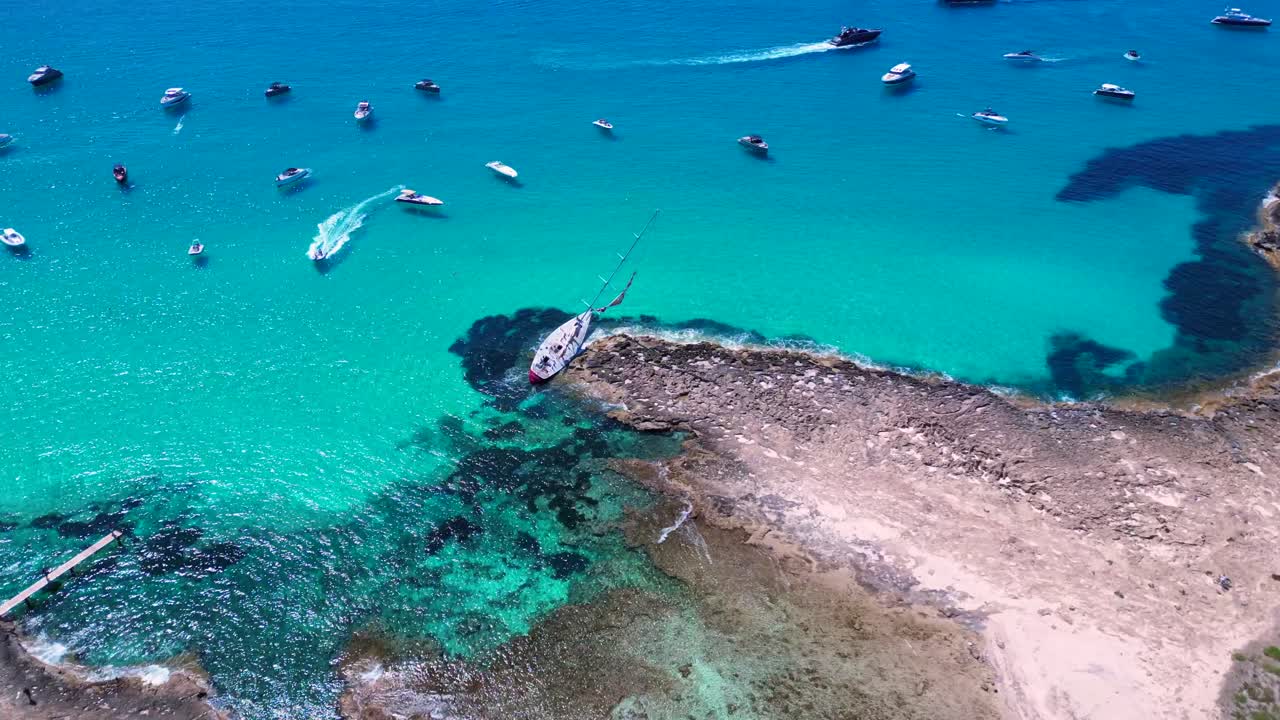 Sailboat stranded on cliff near the coast of Formentera Island, Spain, during a summer sunny day. Magic aerial view flight wide orbit overview drone