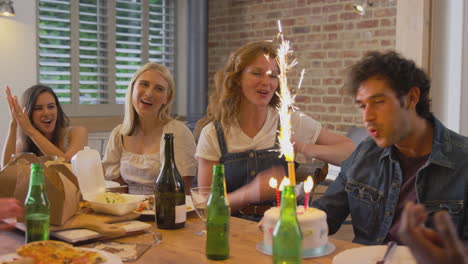 multi-cultural group of friends celebrating birthday with party and cake at home together