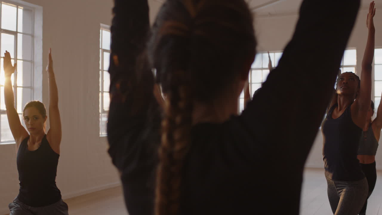 istruttore di lezione di yoga che insegna posa del guerriero gruppo di donne che praticano godendo di uno stile di vita sano esercitandosi in palestra all'alba