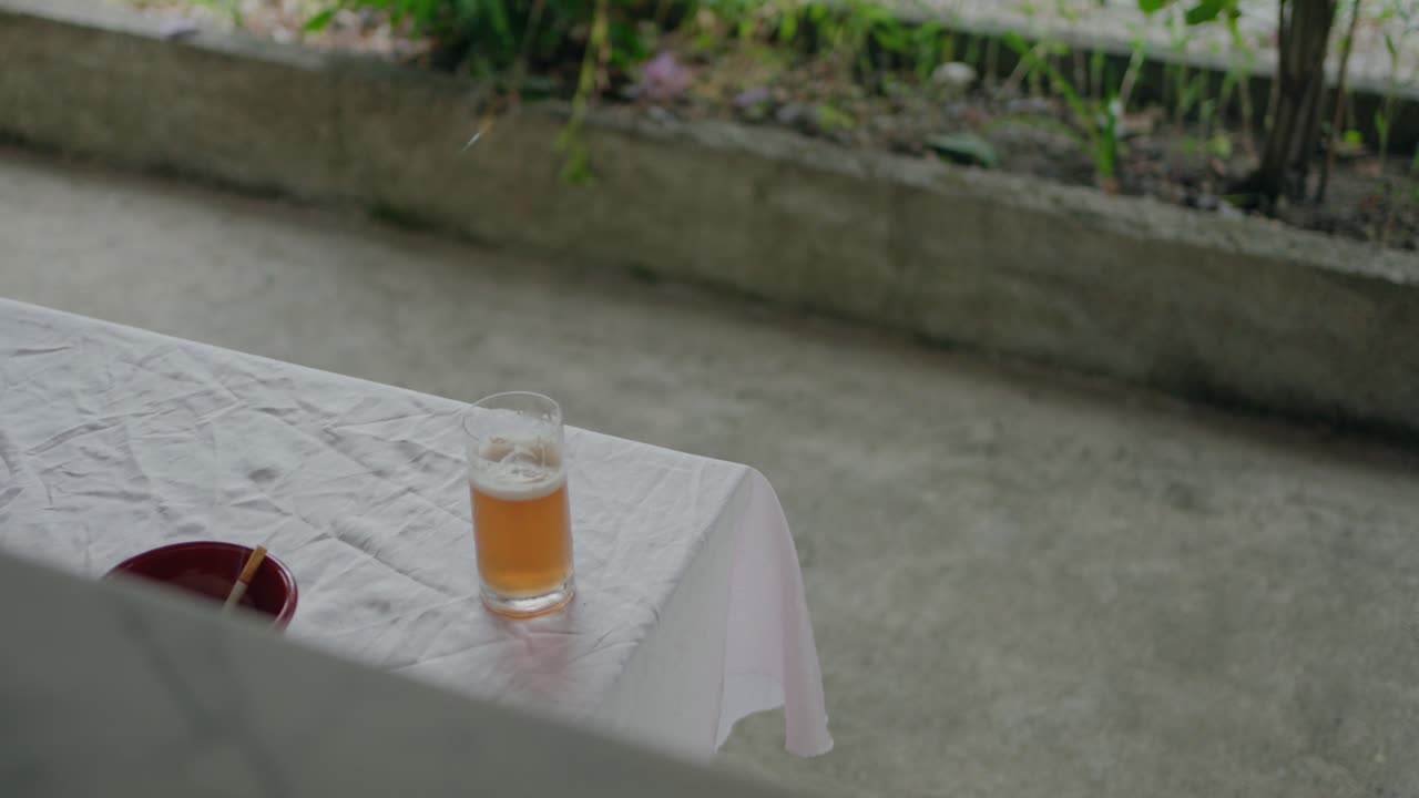 Glass of beer on a table with a white tablecloth, outdoor setting, minimal background