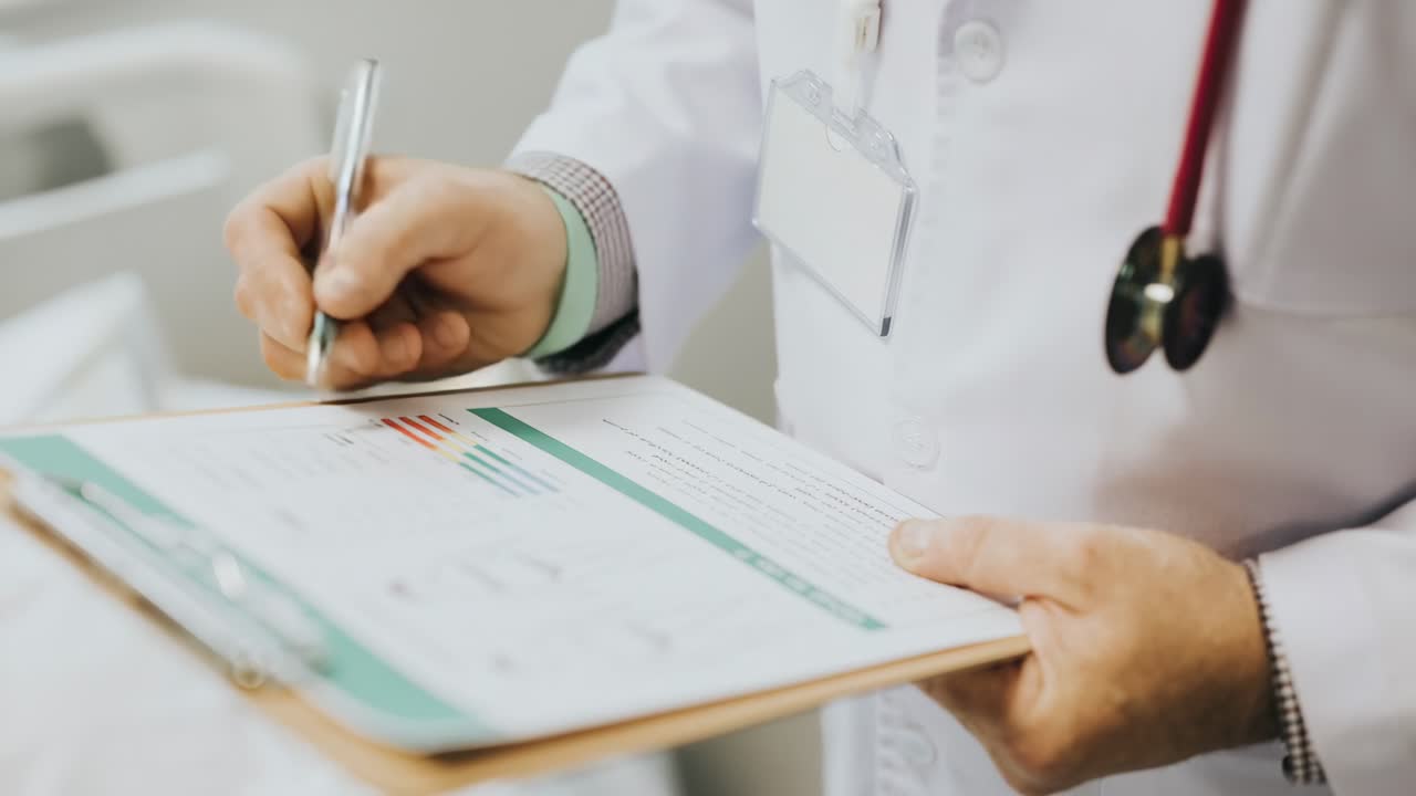 Close-up video angle of a doctor writing on a clipboard, capturing the professionalism and focus