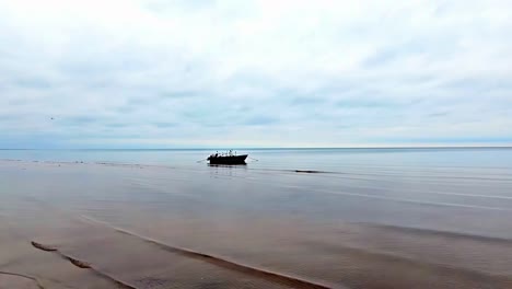 Pequeño-Barco-Pesquero-De-Madera-Flotando-Sobre-Un-Cuerpo-De-Agua-Quieto-En-Un-Día-Nublado