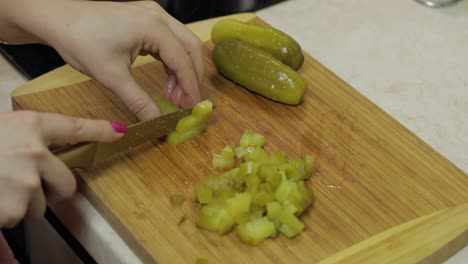 female housewife hands slicing pickled cucumber into pieces in the kitchen