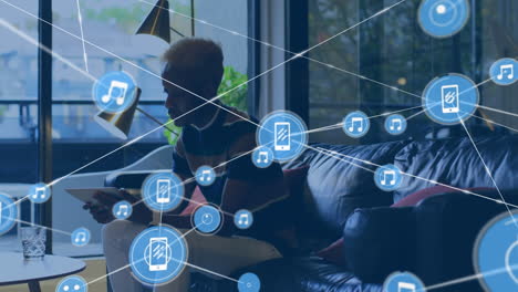 animation of connected icons over african american man drinking water and using digital tablet