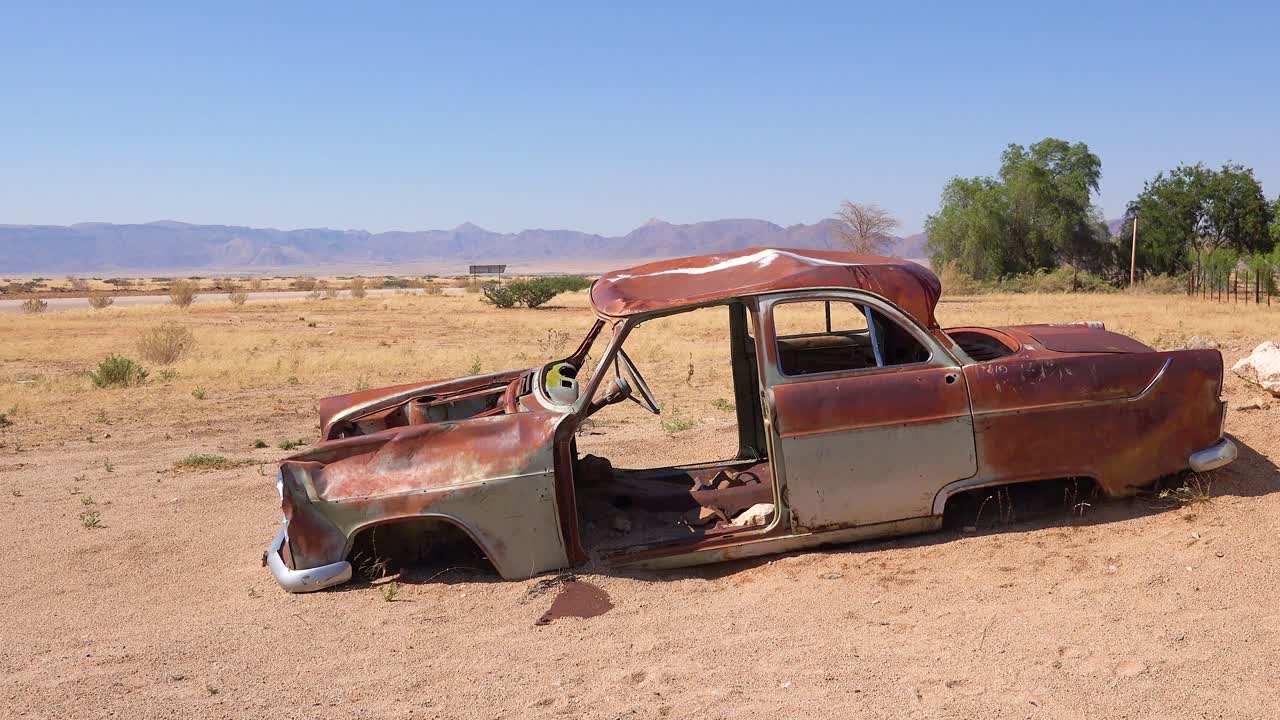 솔리테어 나미비아 1의 작은 오아시스 정착지 근처의 도로에 버려진 녹슨 트럭과 자동차가 줄지어 있습니다.