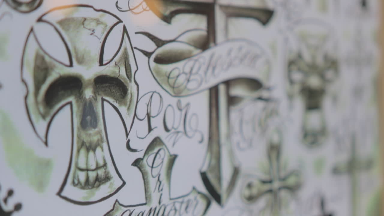 Footage of hand drawn cross tattoo designs at a tattoo shop.