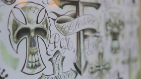 footage of hand drawn cross tattoo designs at a tattoo shop.