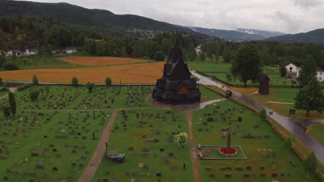 a norwegian church surrounded by a cemetery and scenic landscape, aerial view
