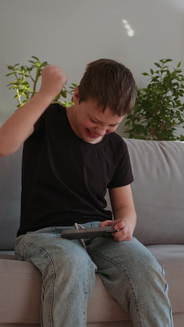 Giovane ragazzo assorto nel giocare a un videogioco su una console, seduto per terra in salotto.