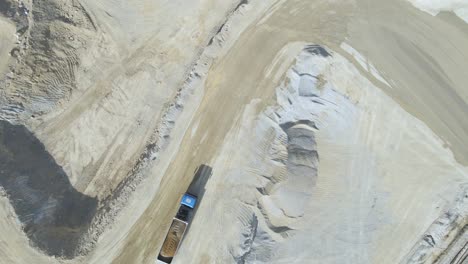 Top-down-drone-shot-rotating-above-a-truck-loaded-with-stones-on-quarry-site