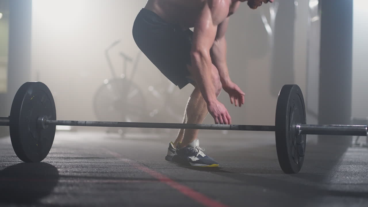 Fitness man doing burpee workout at gym. Medium shot of young man doing push ups and jump exercise in slow motion. Sport concept