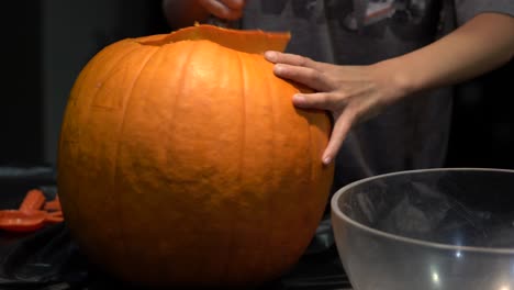 pequeñas manos tirando de la parte superior de una calabaza tallada