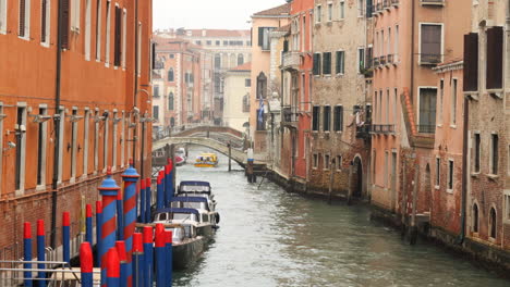 Barco-Pasando-Por-Debajo-Del-Puente,-Barcos-Anclados-Junto-A-Casas,-Canal-De-Venecia,-Italia