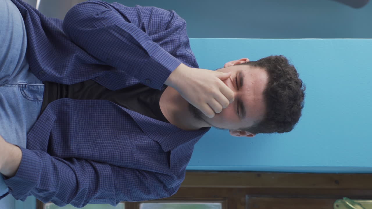 벽  ⁇ 에 앉아 있는 남자가 자기 자신에게 화를 내고 있는 수직 영상입니다.