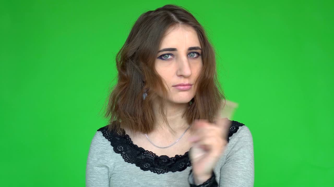 Ritratto di una giovane donna seria che mostra il gesto di stop con il dito su sfondo verde