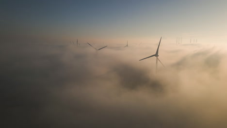 beautiful cinematic aerial shot of wind turbines in the mist - sunrise