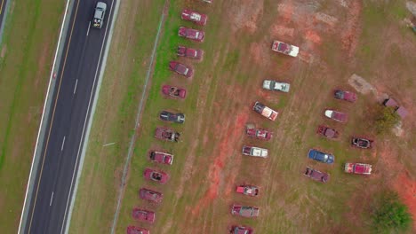 muchos coches antiguos en filas uno al lado del otro oxidado dañado enterrado en el suelo barro alrededor dejado atrás coches modernizados montar conduciendo en la carretera al lado de él vehículo de viaje colores vívidos dron