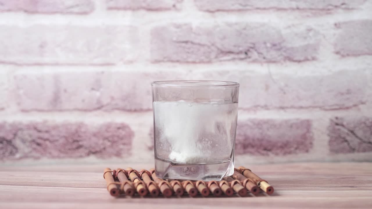 colocando la píldora a mano en un vaso de agua