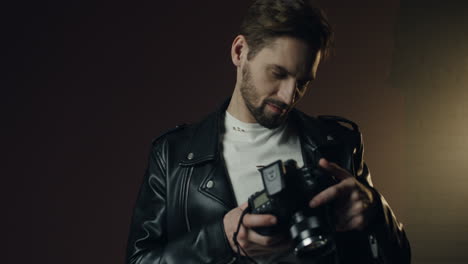 close-up beeld van blanke jonge man in stijlvolle outfit in fotostudio die de camera opzet terwijl hij werkt als fotograaf