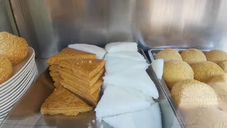 Chinese-traditional-snack-and-dessert-in-porridge-noodles-restaurant,-sesame-balls,-brown-and-white-sugar-sponge-cakes-in-Hong-Kong