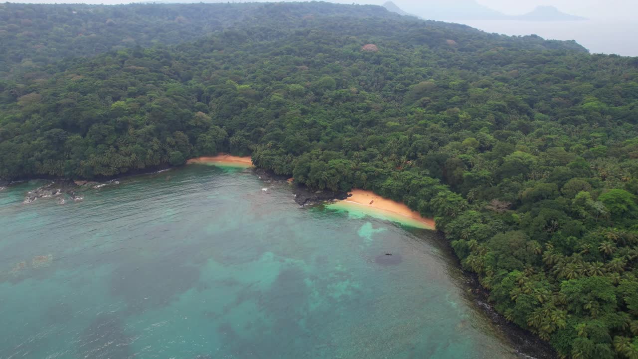 Flying in a circle and rising over the sea with a view of Margarida beach and the island's green forest in the background. Ilha do Principe (Prince Island) Africa