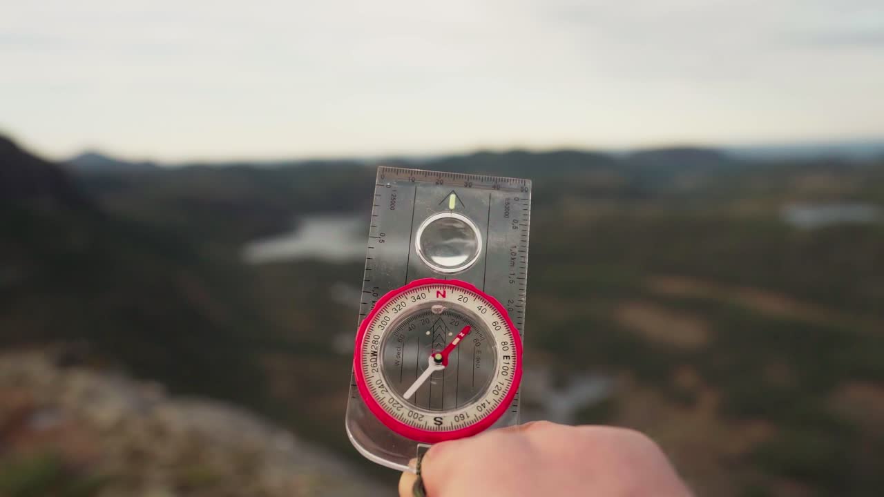 hildremsvatnet, condado de trondelag, noruega - una mano agarrando una brújula - de cerca