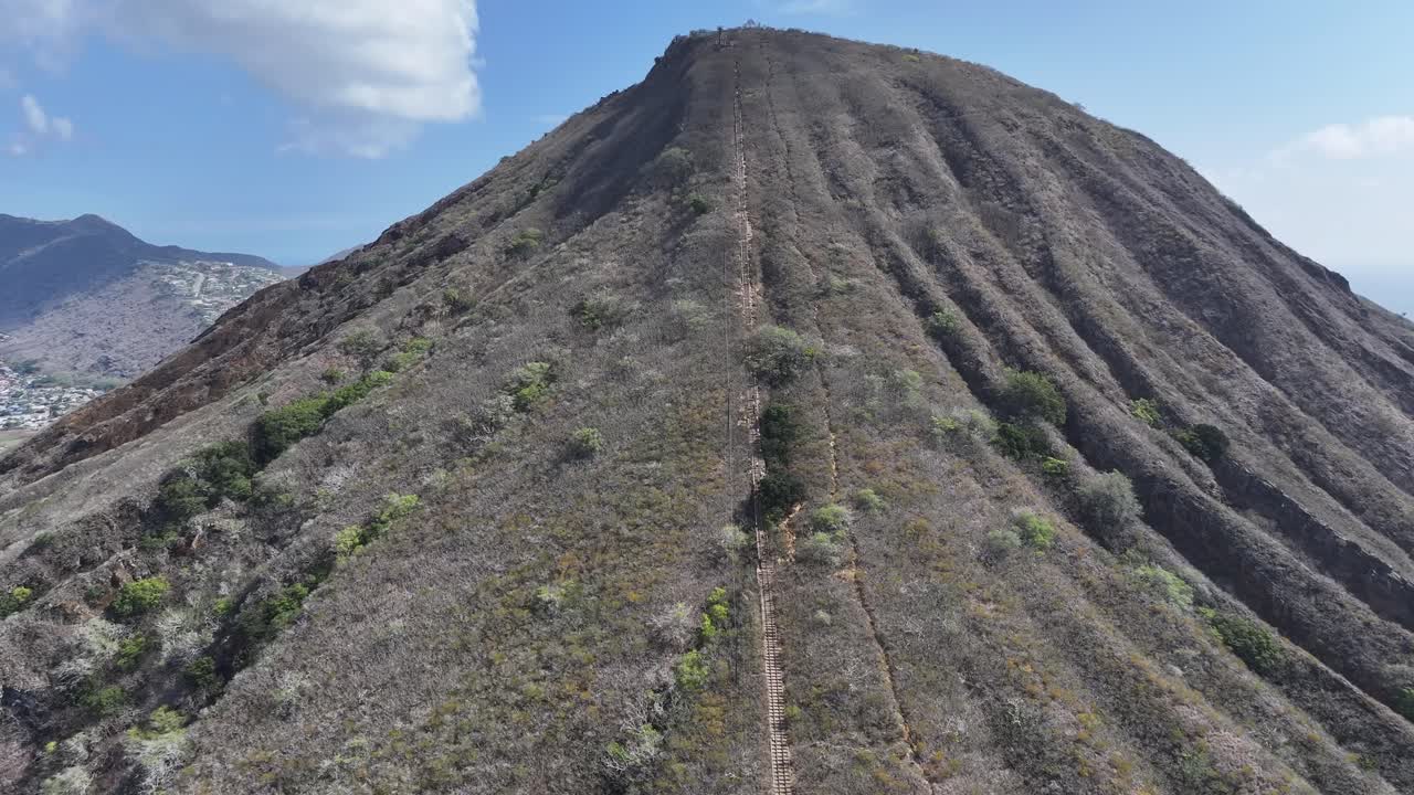 Aerial drone footage flying over the rim of Koko Head volcanic crater on Oahu, Hawaii, showcasing rugged cliffs, tropical landscapes, panoramic ocean views, and the island’s dramatic volcanic terrain