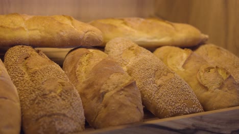 Bäckereiregal-Gefüllt-Mit-Frisch-Gebackenen-Goldenen-Brötchen,-Brothintergrund