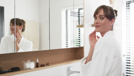 Middle-aged-Caucasian-woman-applies-skincare-in-a-bright-bathroom