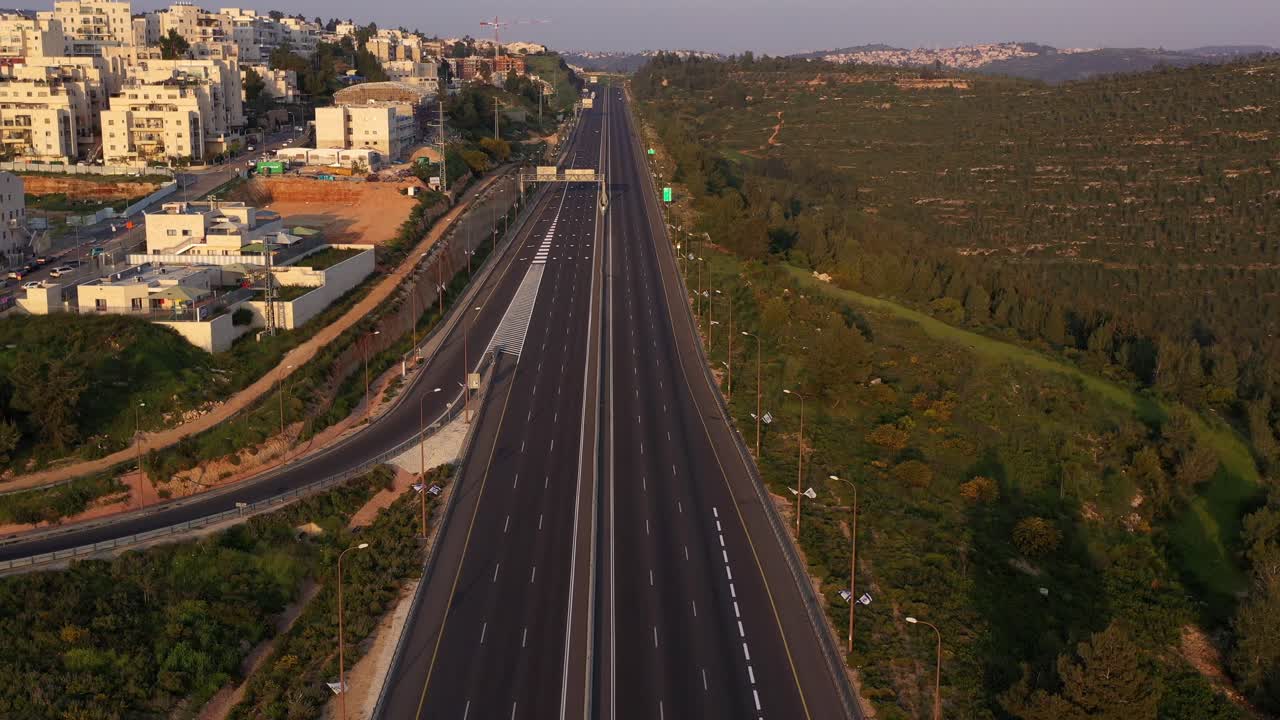 Aerial View of a Multi-Lane Highway Next to a Residential Area and Green Hills