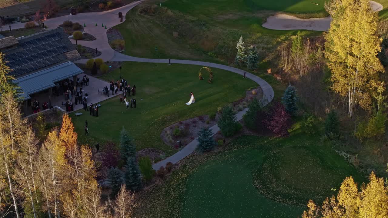 Scenic aerial orbit reveals bride walking along a mountain golf course, surrounded by vibrant autumn foliage in Vail during wedding season