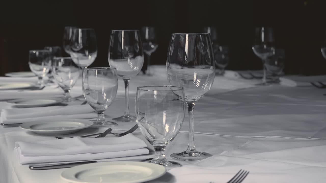 mesa de comedor para una boda o evento corporativo en un restaurante de alta cocina platos de cerámica tenedores cuchillos servilletas de tela sobre un mantel blanco en la mesa a cámara lenta inclinada hacia la derecha
