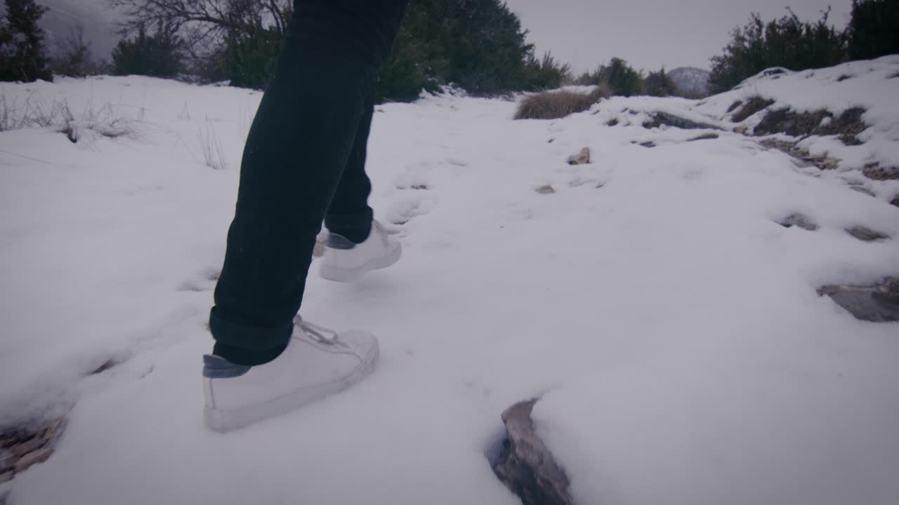 차분한 겨울 자연 속을 걷고, 눈을 밟고 있는 발이 가까이