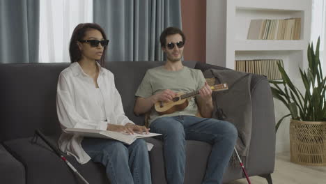 front view of blind friends sitting on a sofa in a flat