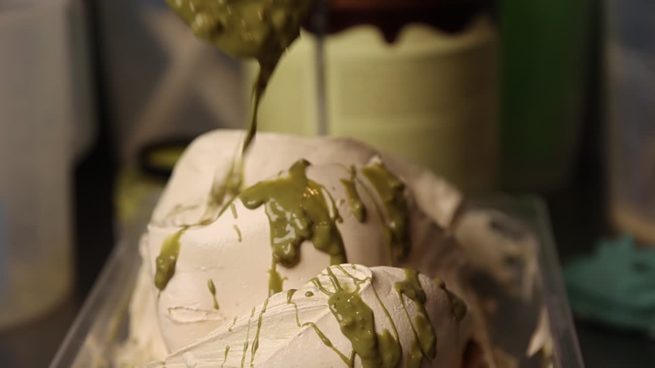 Grøn sauce dryppende over cremet hvid gelato