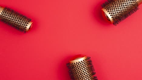 stop motion animation flat lay from above set of professional gold round hair brushes for styling template with copy space on red background. hairdresser salon equipment concept, premium set