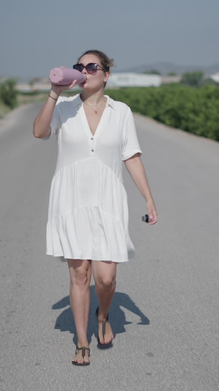 Woman drinking from water bottle on road