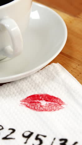 primer plano de una taza de café con marca de lápiz labial y mensaje escrito en el tejido