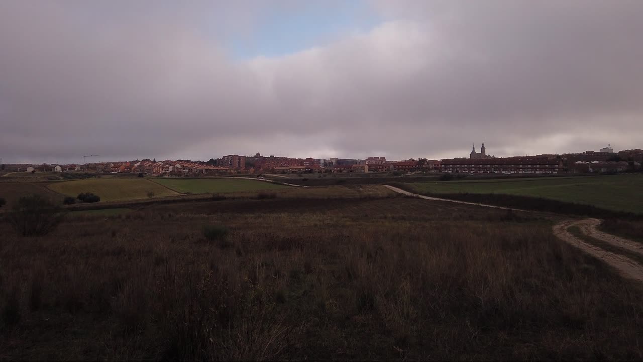 un lapso de movimiento de un pequeño pueblo, moviéndose hacia la derecha, a un camino de tierra que termina en el pueblo