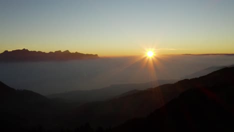 slow aerial shot of the sun setting over sea of fog